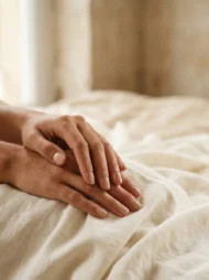 Mains féminines aux ongles nus soignés sur lin ivoire sous une douce lumière zénithale